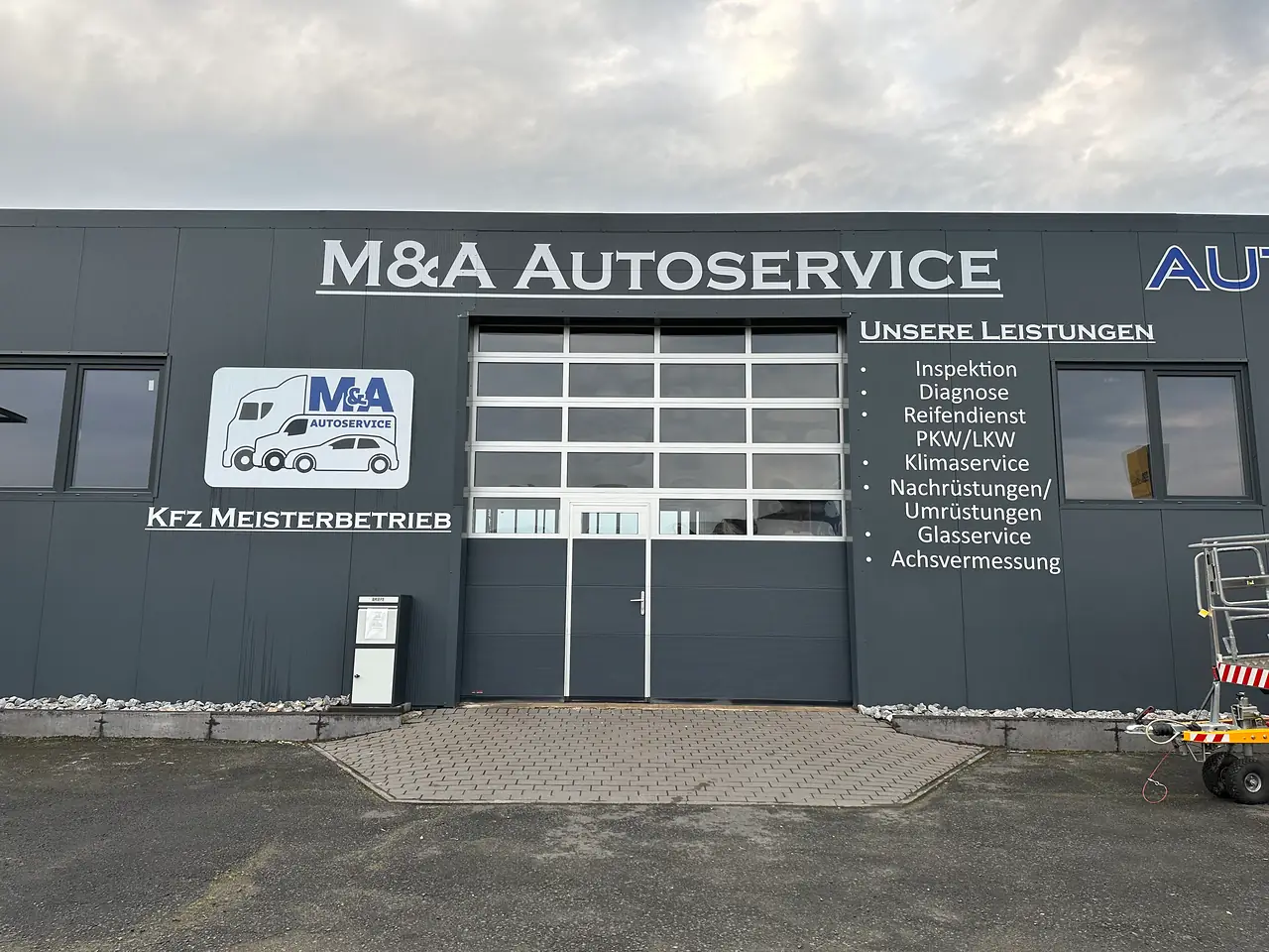 Fassade mit Firmenname, Logo und Leistungsliste neben dem Hallentor