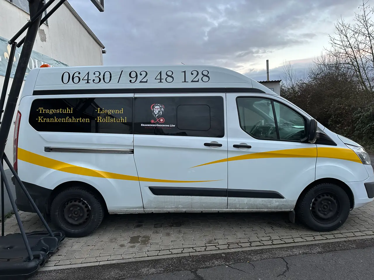 Ford Transit Hochdach mit Telefonnummer auf dem Dach und gelbem Schwung