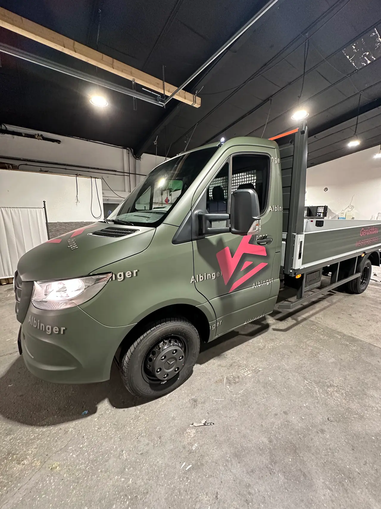 Mercedes Sprinter in mattem Militärgrün mit rotem Logo in der Halle